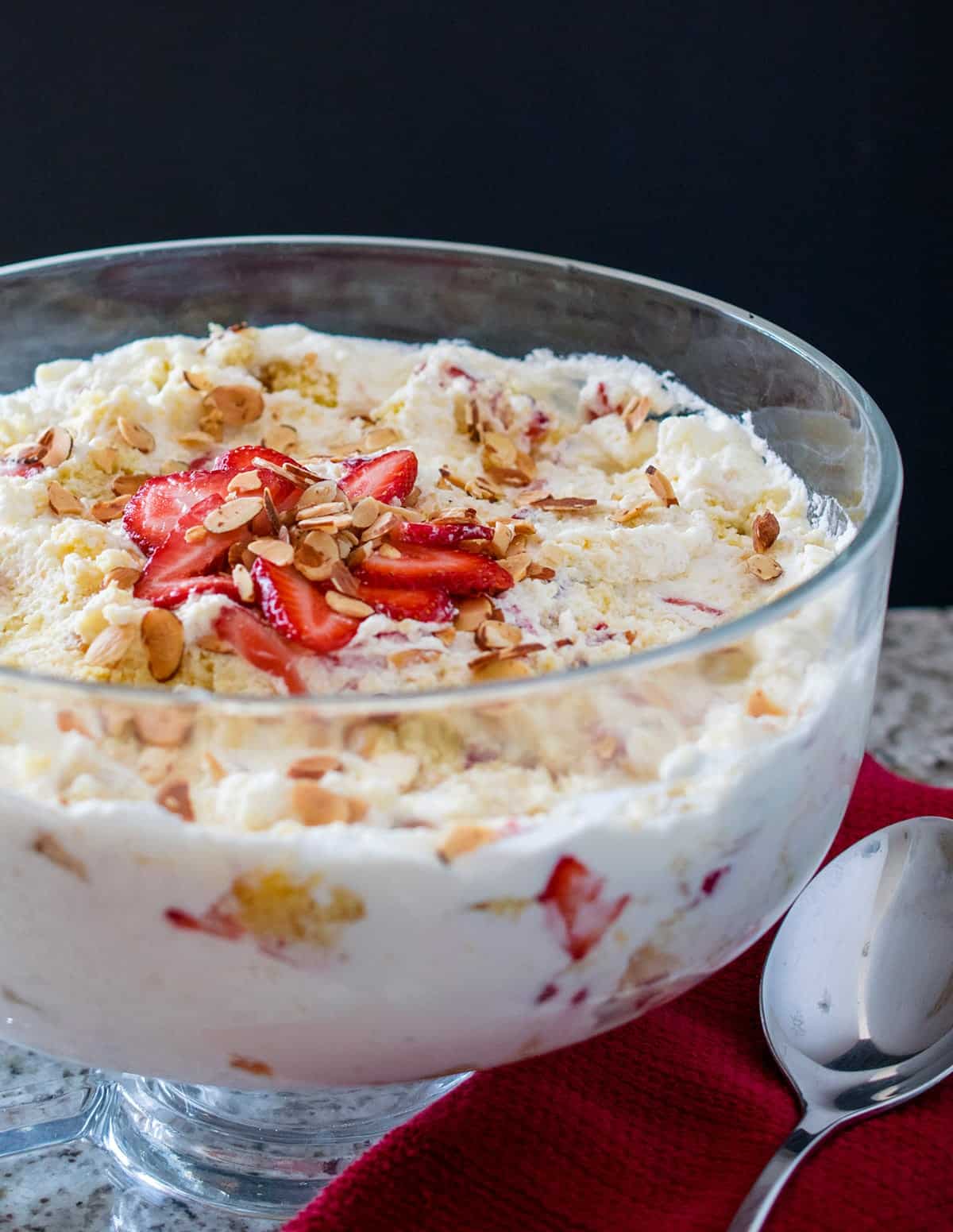 Punch Bowl Cake with Strawberries and Pineapple with whipped topping plated in large glass trifle dish.