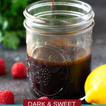 Raspberry Vinaigrette dressing in a jar with a spoon above containing dressing dripping.