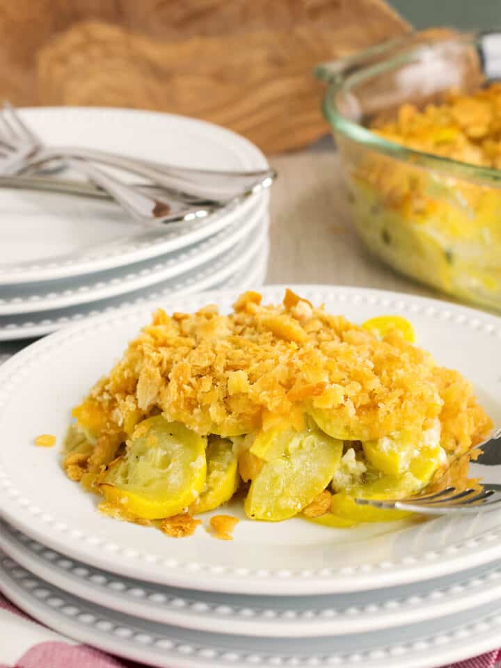 Squash casserole with ritz cracker toping as a side dish served on a stack of plates.
