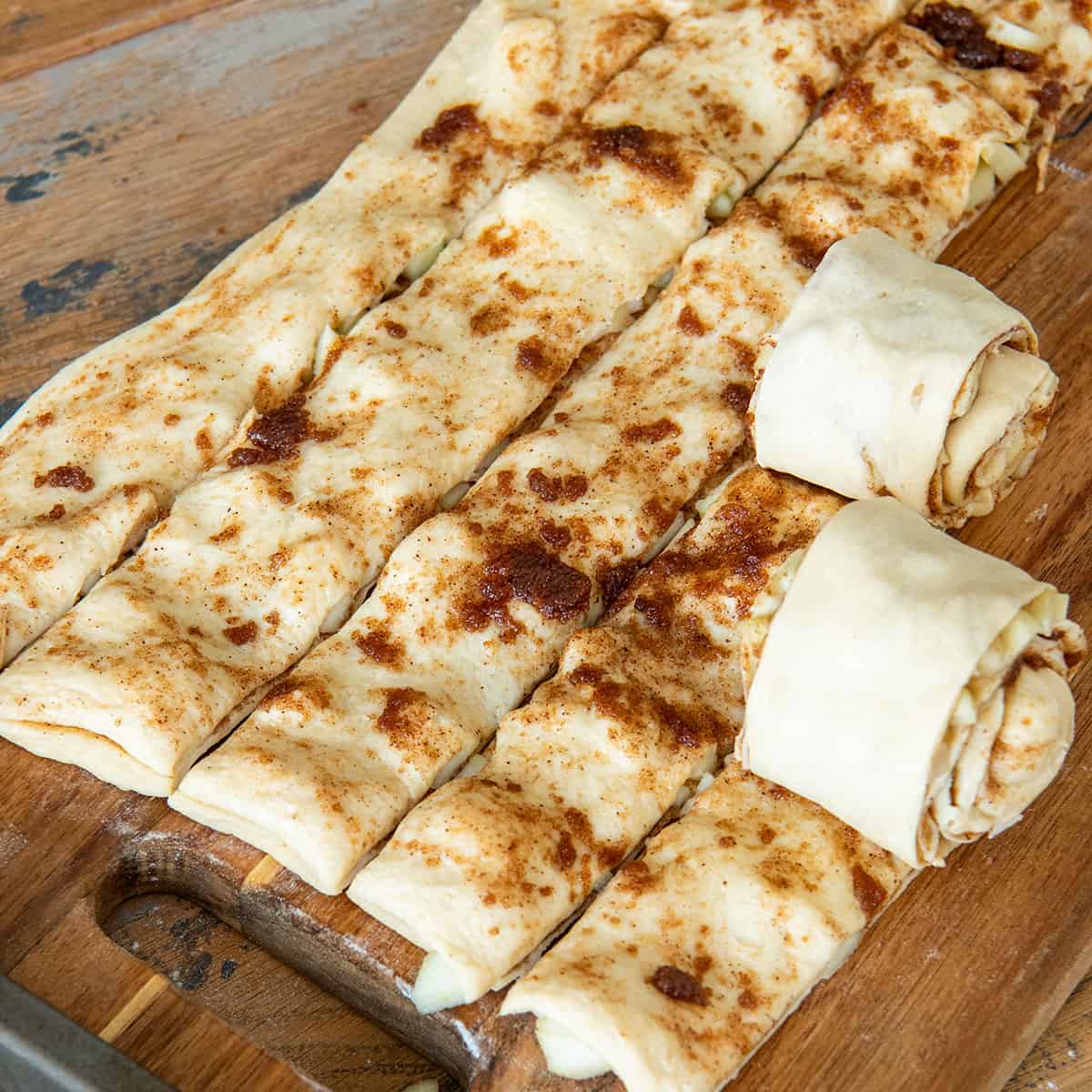 Cinnamon rolls being rolled up in lines.