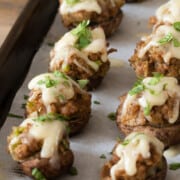Sausage stuffed mushrooms on a sheet pan topped with swiss cheese and parsley.