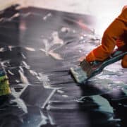 Woman cleaning a glass stove top with a flat scraper.