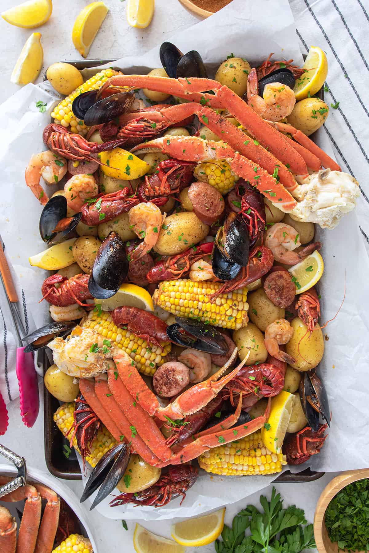 Seafood boil overhead on a table with crab legs, mussels, crawfish, potatoes, corn, and Cajun butter sauce.