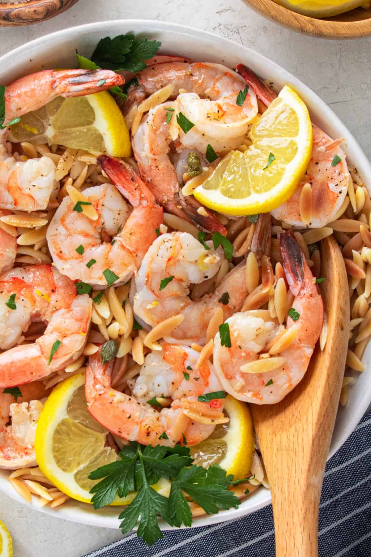 Overhead closeup of garlic shrimp orzo with lemon slices and parsley in a bowl.