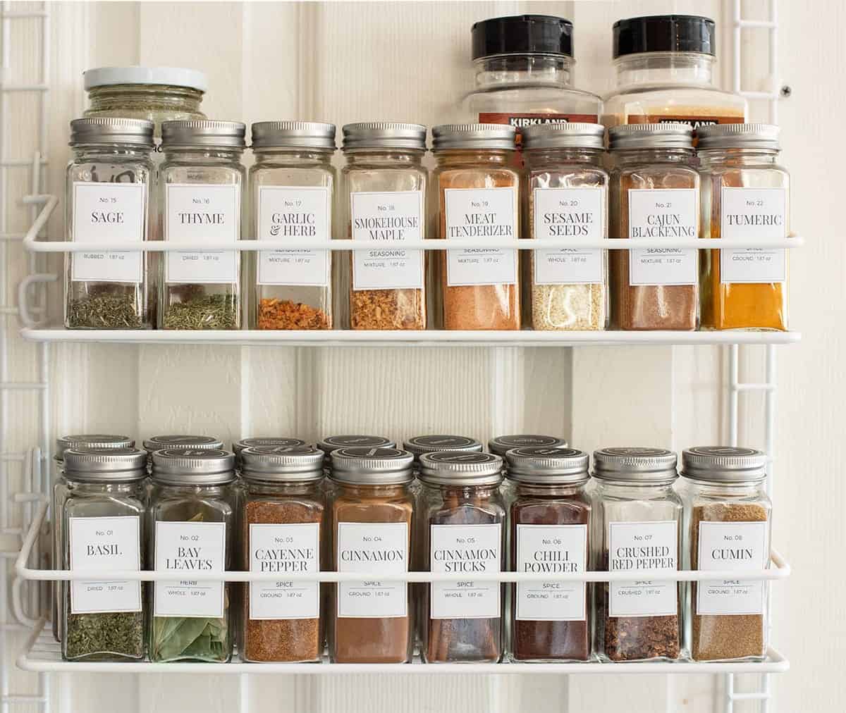 Spice rack organization with labeled spice containers on the back of a door.