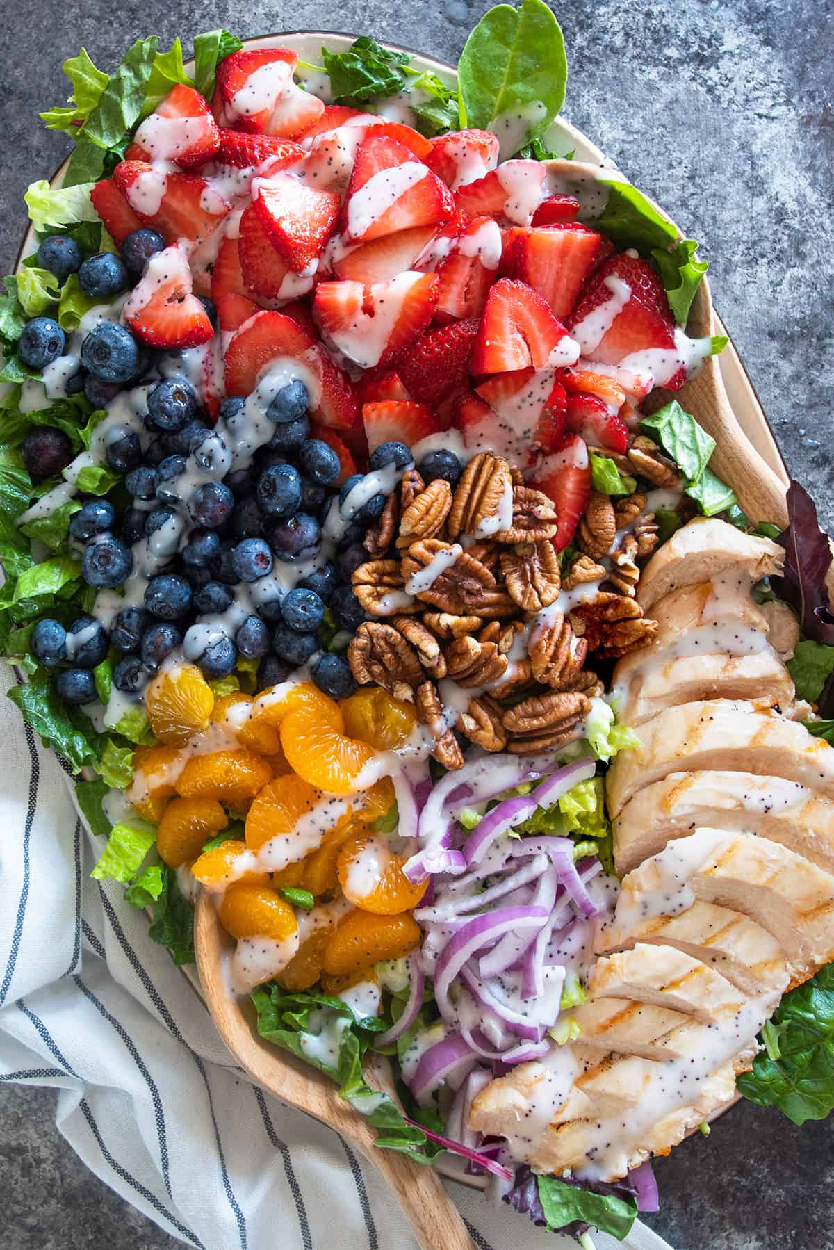 Strawberry Poppyseed salad on a platter with blueberries, mandarin oranges, pecans, red onions, and grilled chicken.