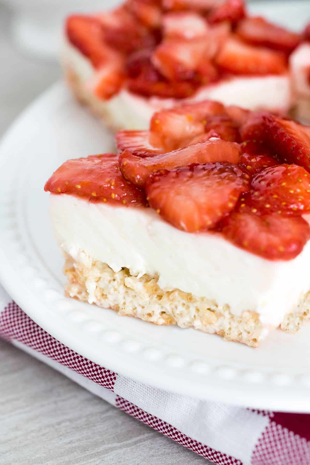 closeup of no bake cheesecake with rice krispies crust topped with fresh sliced strawberry topping.