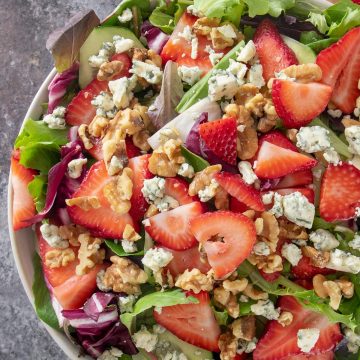 Strawberry spinach salad with feta crumbles and pecans in a salad bowl.