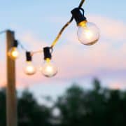 Outdoor wooden deck post with row of patio string lights.