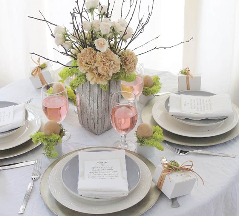 Elegant simple easter table with flower centerpiece and menu place settings.
