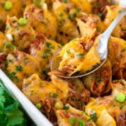 Taco stuffed shells in a large white pan with cilantro as garnish.