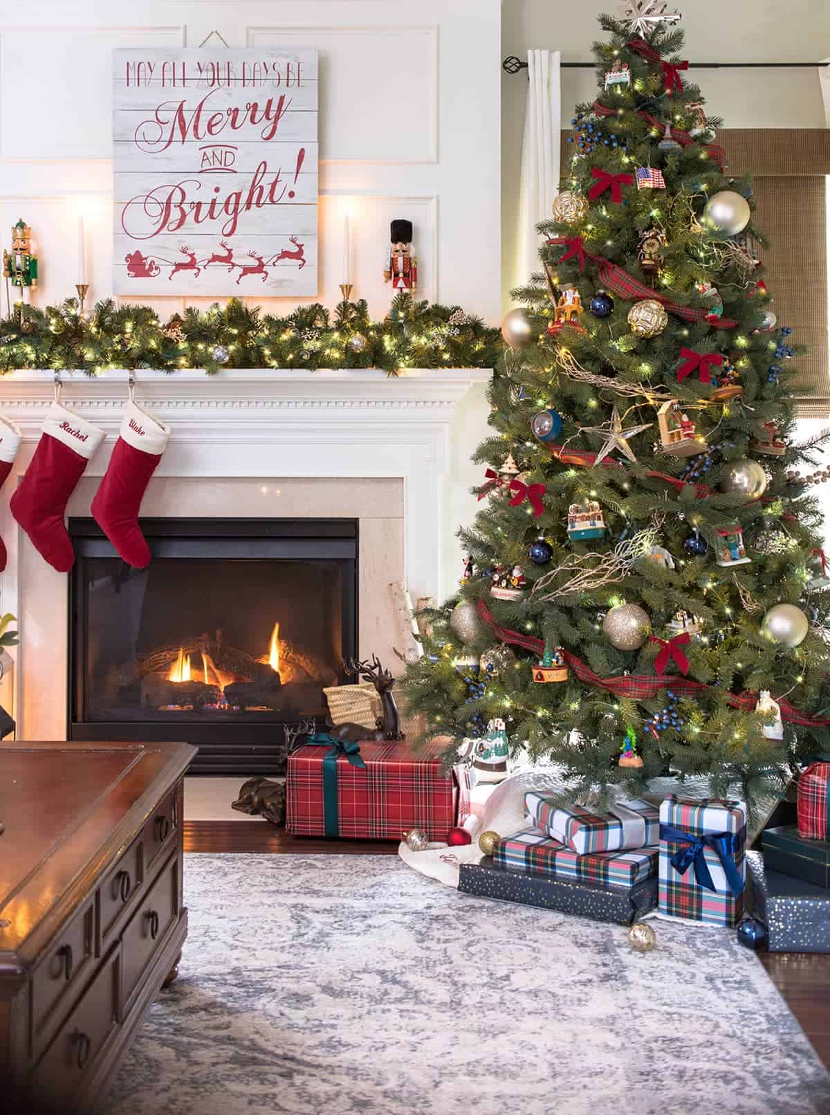 Traditional Tartan Plaid Christmas Tree Decorations in family room with fireplace aglow and presents stacked under tree.