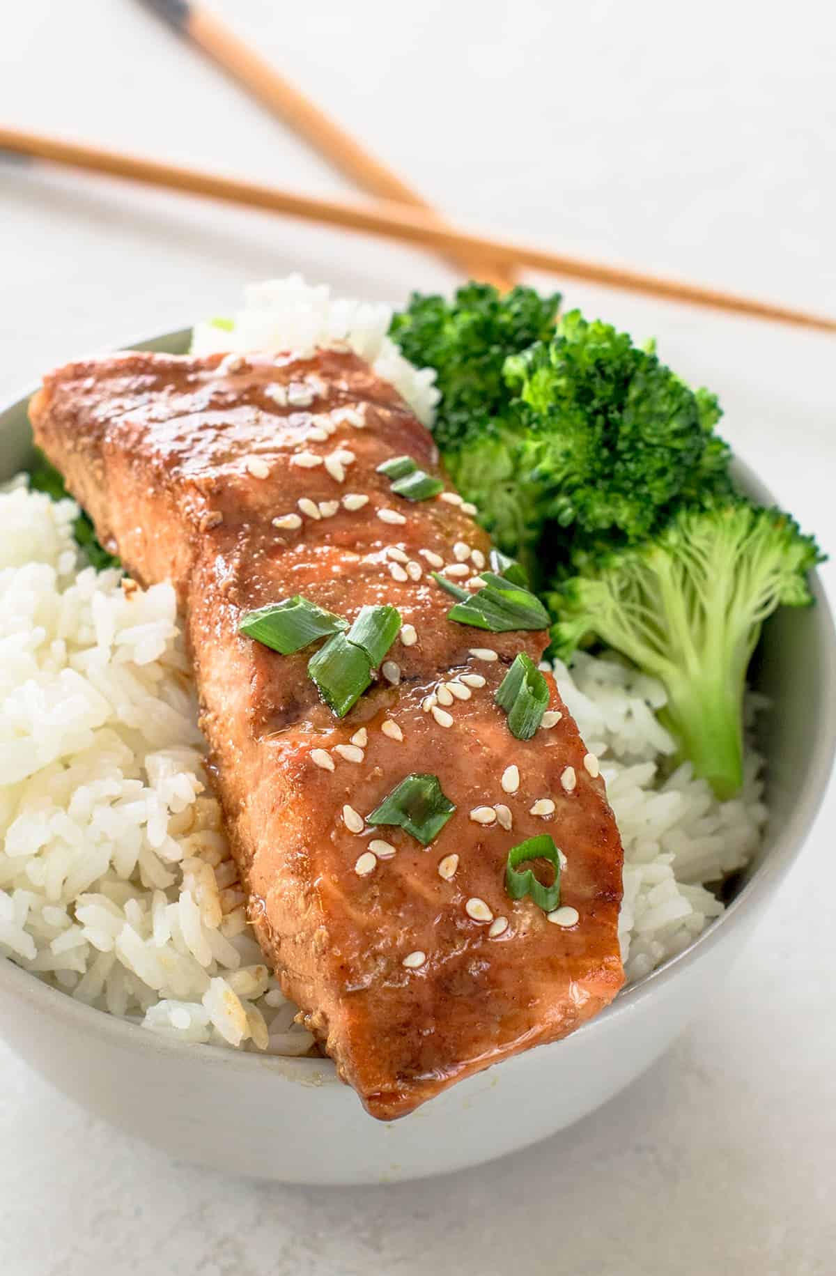 Baked Teriyaki Salmon over a rice bowl with broccoli florets on the side.