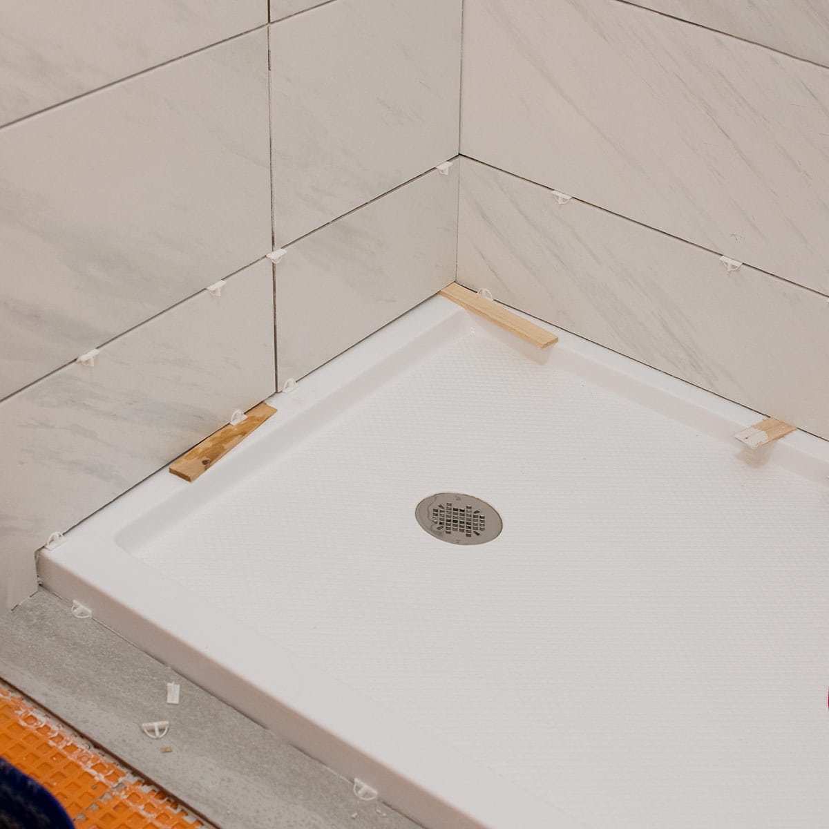 Shower pan being tiled with spacers inserted to keep tile in place.