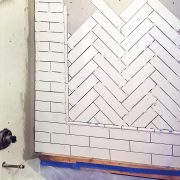 In progress photo of laying herringbone pattern with ceramic tile inset with subway tile surround.