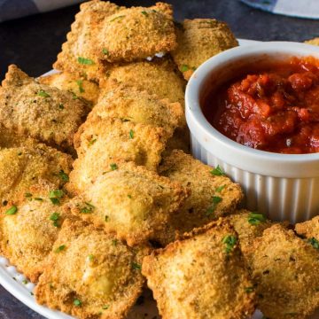 Toasted ravioli rolled in bread crumbs and piled next to marinara dipping sauce for serving.
