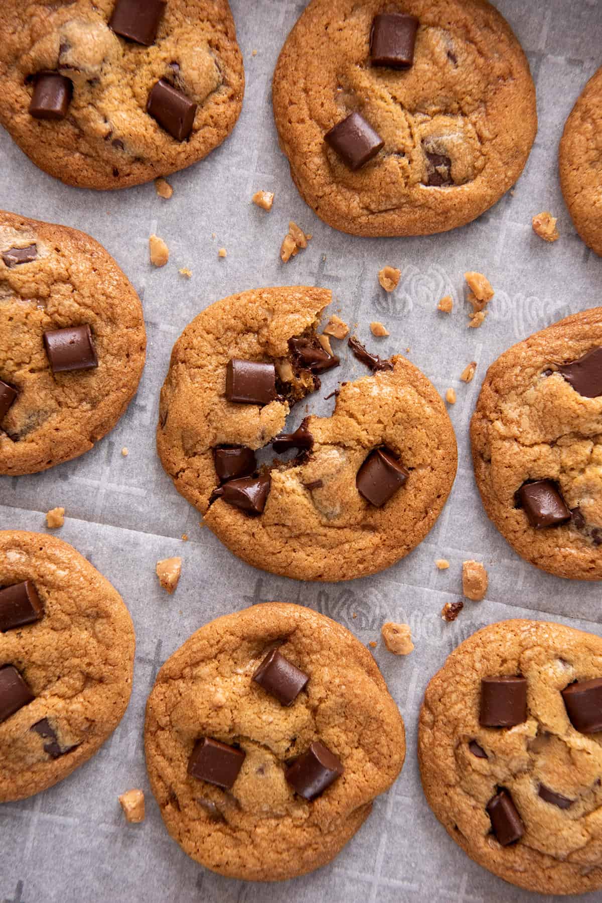 Overhead of toffee cookies with one in the middle broken to show melty chocolate chips.