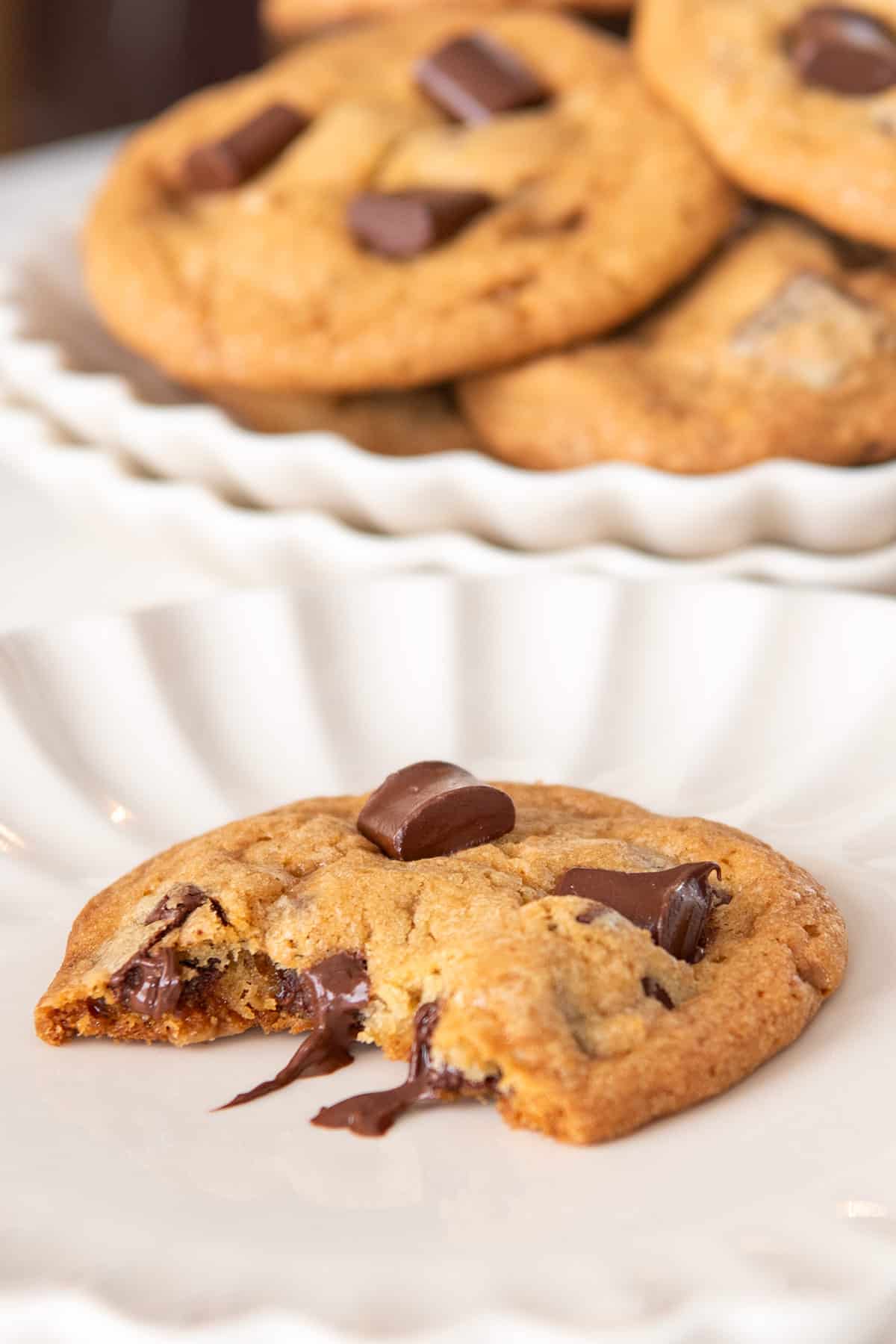 A cookie with a bite taken out to show inside texture on a cream plate.