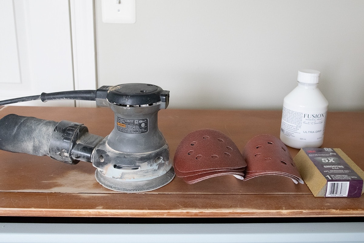 Tools for painting furniture including orbital sander, sanding pads and blocks, and adhesive primer.