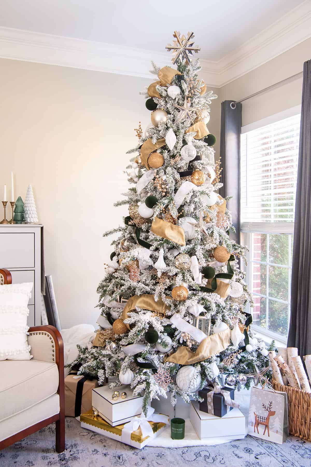 Elegant white and gold christmas tree with olive green or black accents including ribbon and ornaments.
