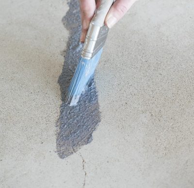 Brushing Behr Granite Grip on floor with a paint brush.
