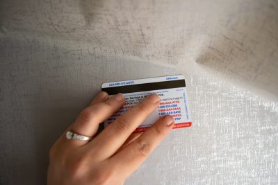 Hand removing air bubbles from applied contact paper with plastic card.