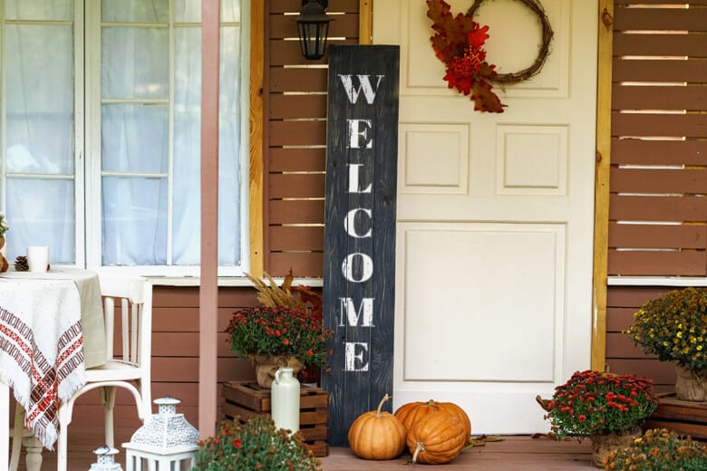 Black DIY welcome sign on front porch decorated for fall.