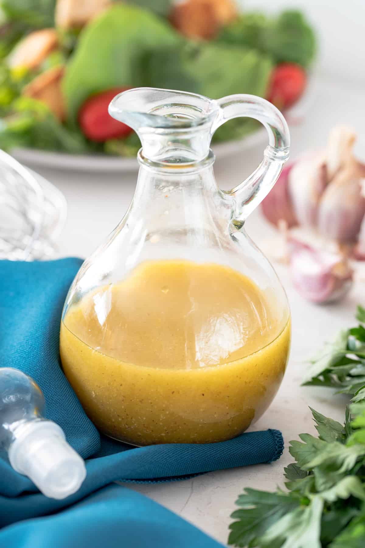Cruet Bottle of White Balsamic Salad Dressing with ingredients scattered around.