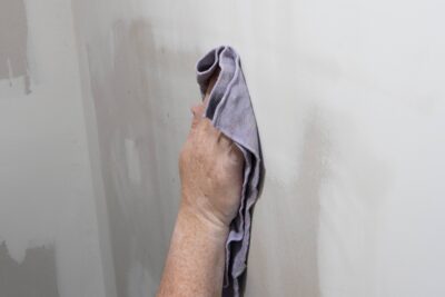 Closeup of a hand wiping drywall dust after patching and taping.