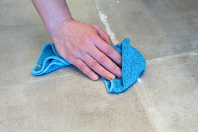 A closeup of a hand wiping tile for cleaning.