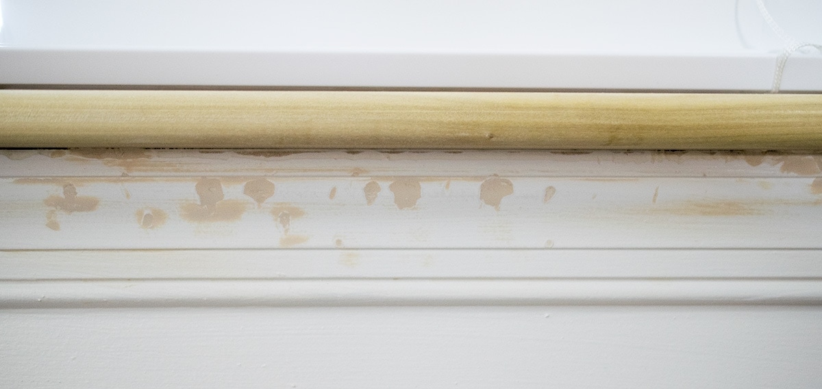 Damaged door casing under a window with wood filler in the chew marks.