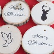 Two rows of wood slice ornaments with Christmas themed image transfers on red surface.
