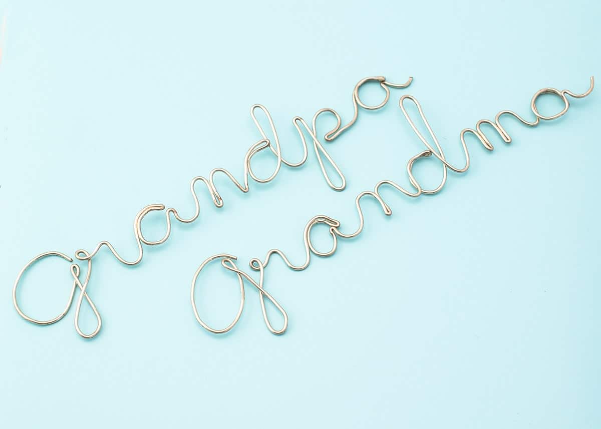 DIY wire art showing the words Grandma and Grandpa in cursive writing art on blue surface.