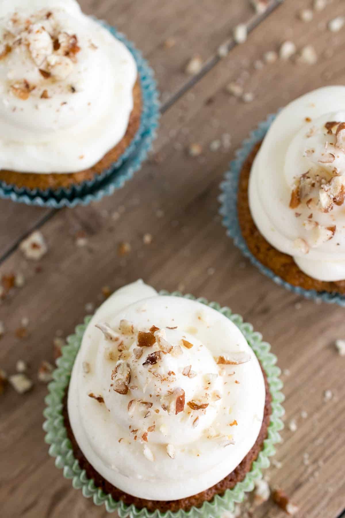 Carrot Cake Cupcake with classic Cream Cheese Frosting with chopped walnuts on wooden cutting board